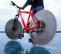 Utiliza hojas de sierra en su bicicleta para poder pasear sobre un lago congelado.